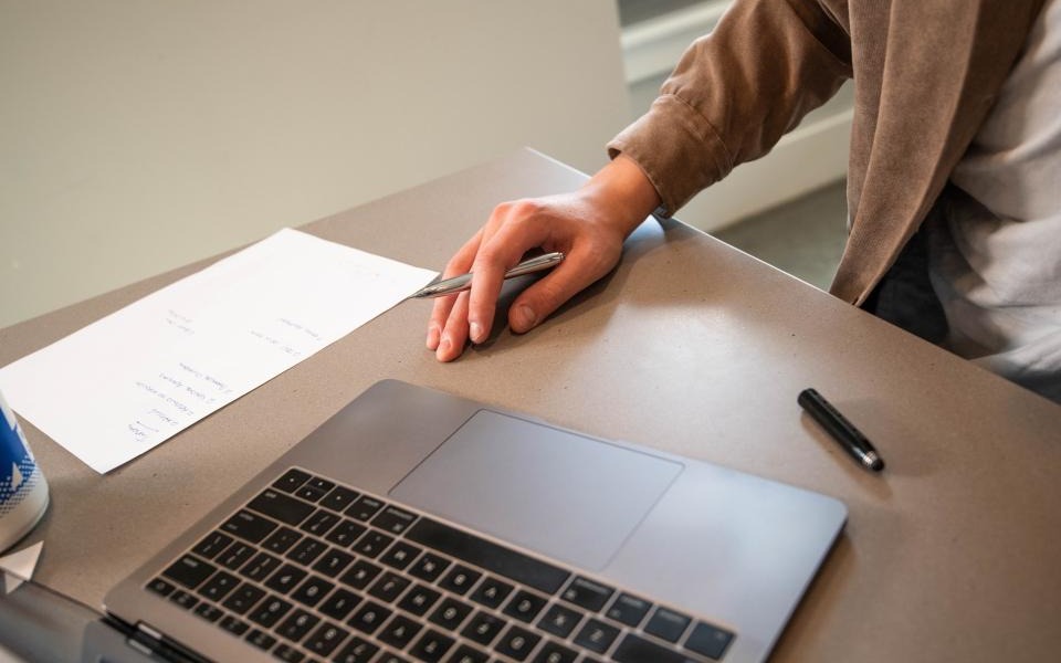 Hand mit Laptop und Stift